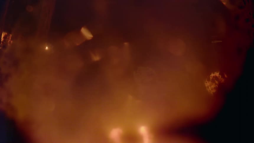 Particles under a microscope with a red tint and bright light cast across the lamp
