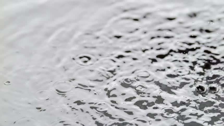 Water droplets dropping onto the water surface creating ripples on the surface during the day