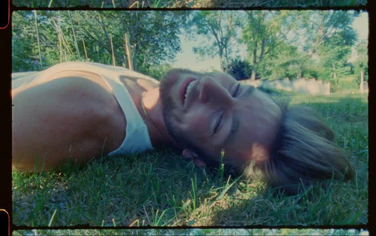 Blonde bearded happy man lays in the grass smiling