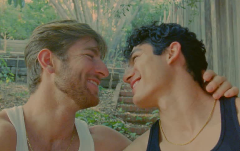 Two men smile while staring into each others eyes near base of outdoor steps