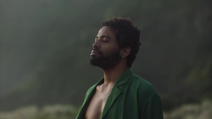 Man standing outdoors closes his eyes to bask in nature