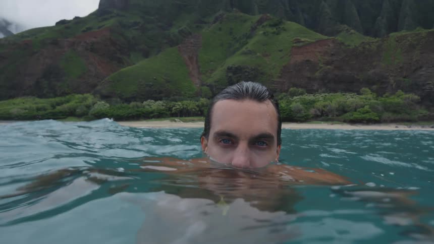 A shirtless man is floating in the water far from land