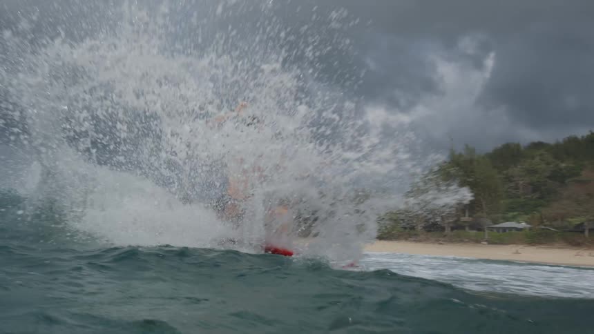 A man surfing a wave with a red colored board