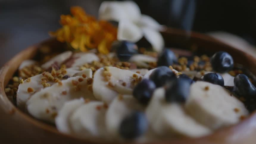 Blueberries sprinkled atop bananas on acai bowl