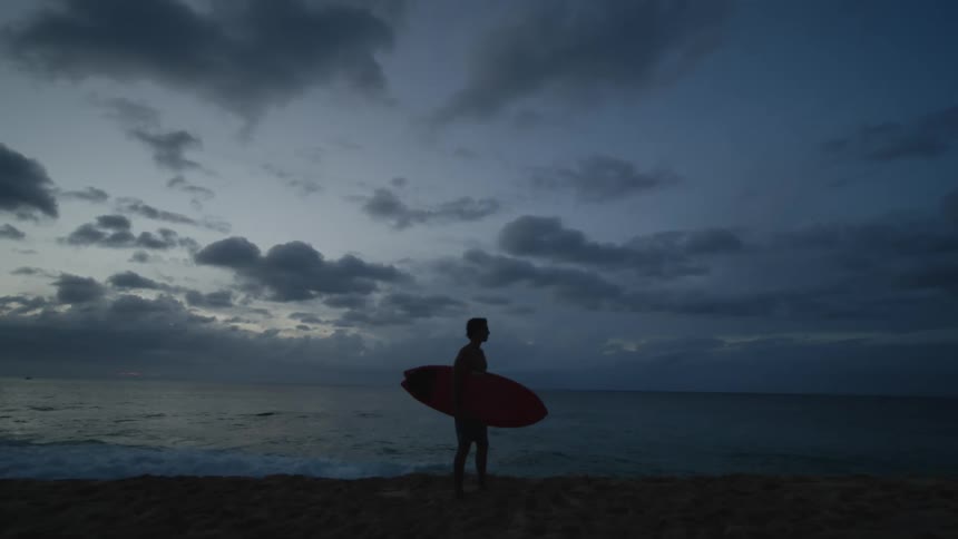 A man with a surfboard in his arms at the seaside