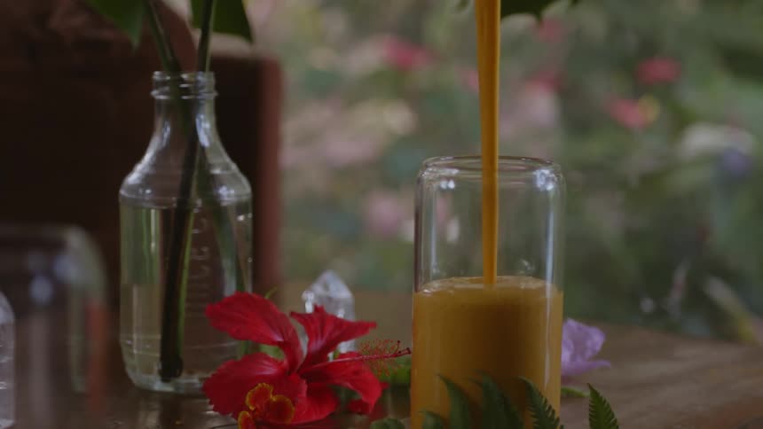Fruit juice is being poured into a glass