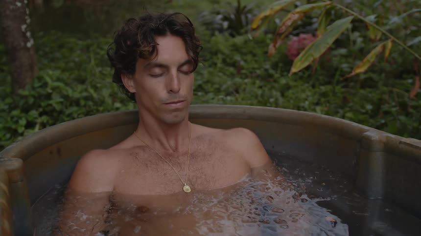 A man taking a deep breath shirtless inside an icefilled bathtub