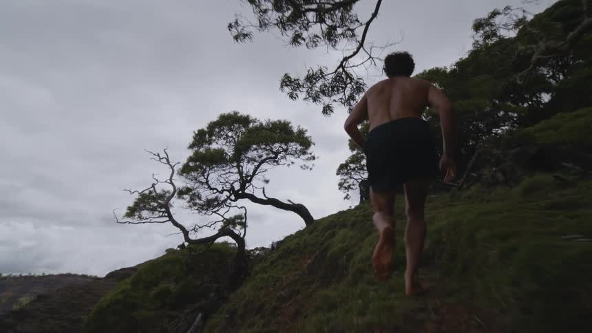 A man running on a mountain with trees at dusk