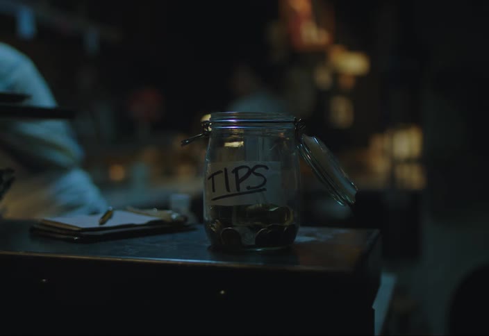Closeup of a tip jar where people leave tip coins in a restaurant setting