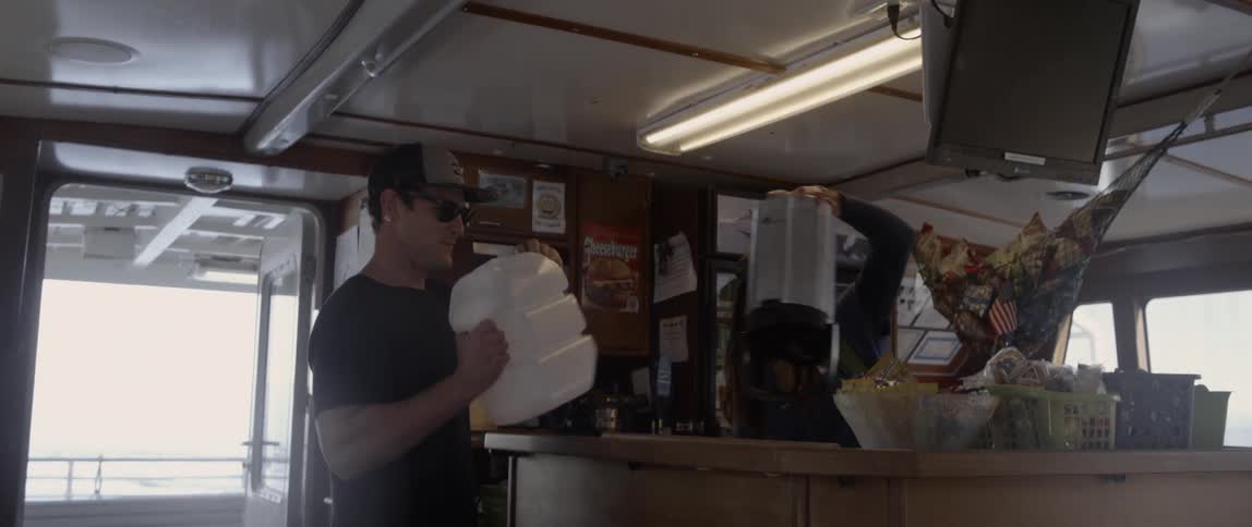 A man walks over to a counter to open a plastic bottle