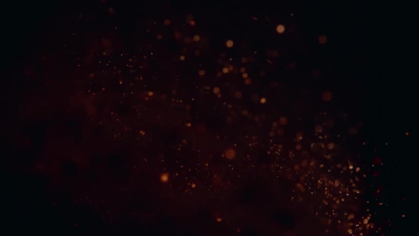 Lots of orange particles flying in different directions and fading with time