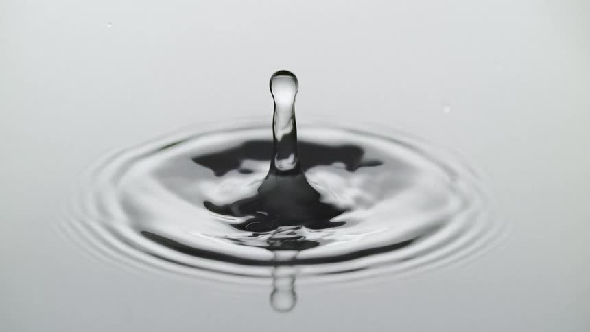 Water drop falling on water in slow motion causing ripples and splashes