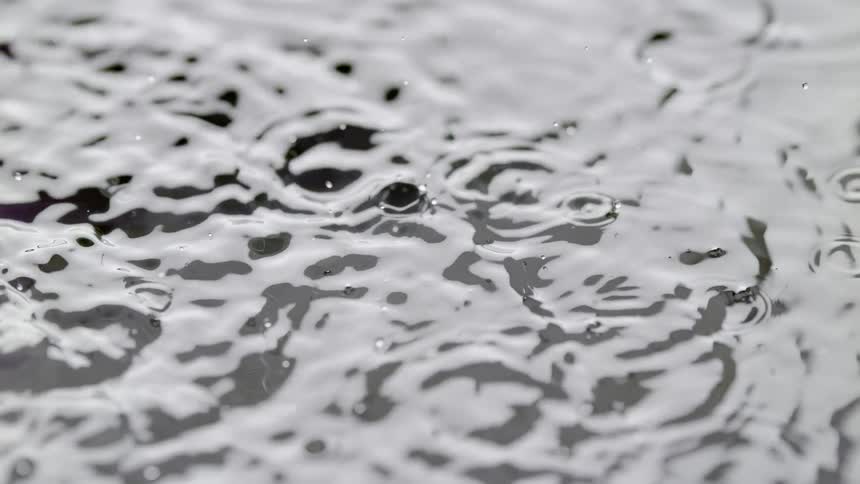 Drops of rain fall onto water causing ripples