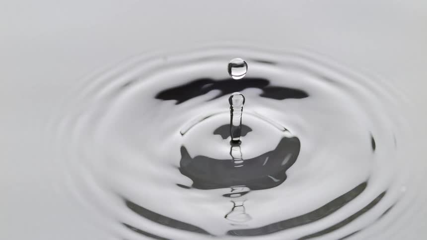 A drop of water falls into a water surface causing circular ripples
