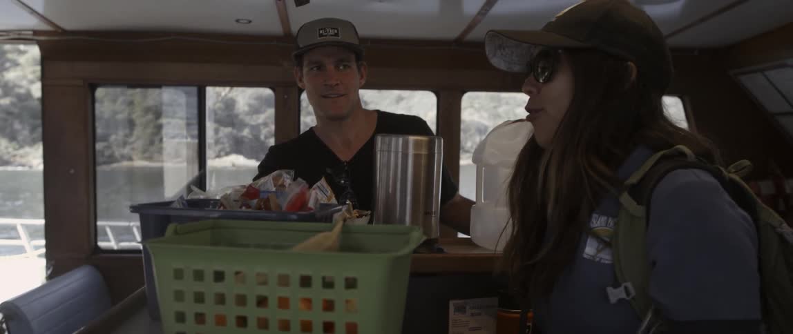 A man and woman talk inside the cabin of a boat