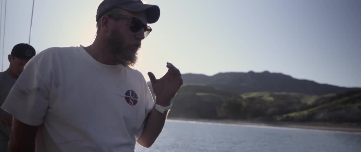 A man talks while standing on a boat holding a wrench