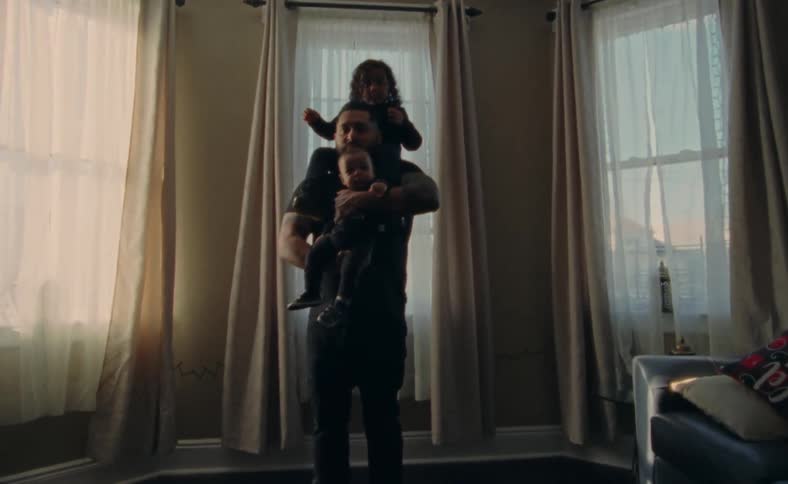 Daughter on dad shoulders while he holds a baby at home