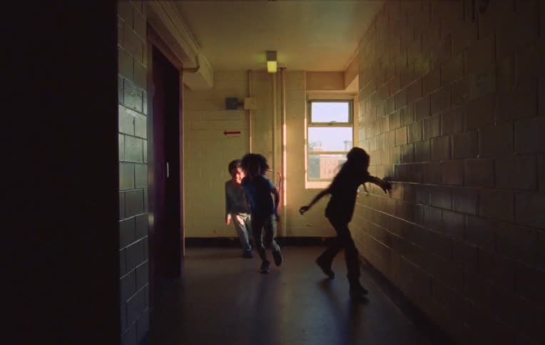 Three children playing and running in a hallway of a building