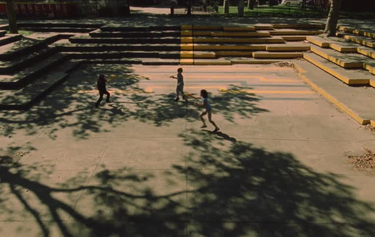 Children play in a courtyard surrounded by trees