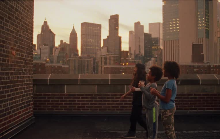 Three kids smatching things into the wall of a building in the city