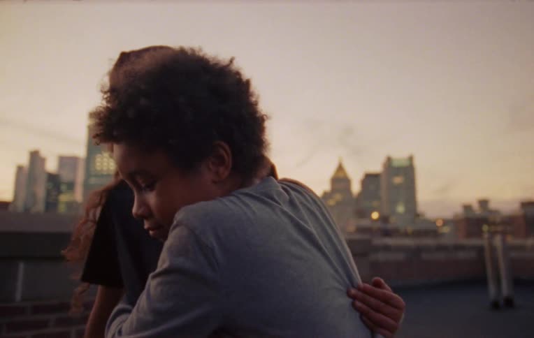 Boy and girl hug on the rooftop of a building in the city at evening