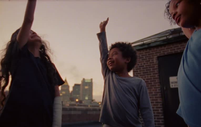 Three kids playing at the top of a roof