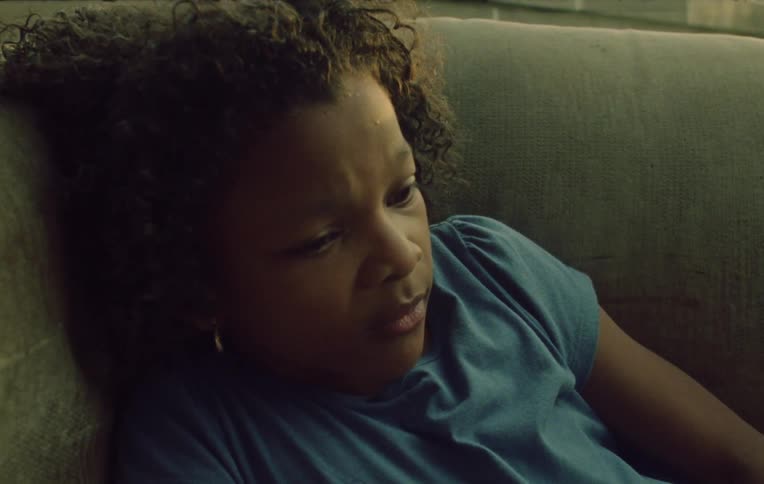 A female lays on the couch holding a glass looking distressed