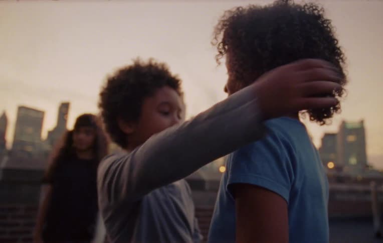 Three children high five and hug on a city rooftop