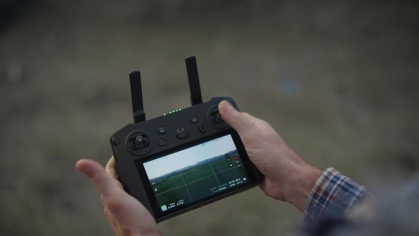 A person controlling a drone with a remote control that has a camera display