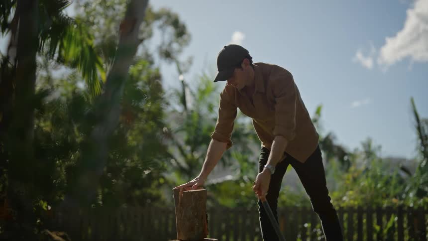 A man uses an ax to split wood