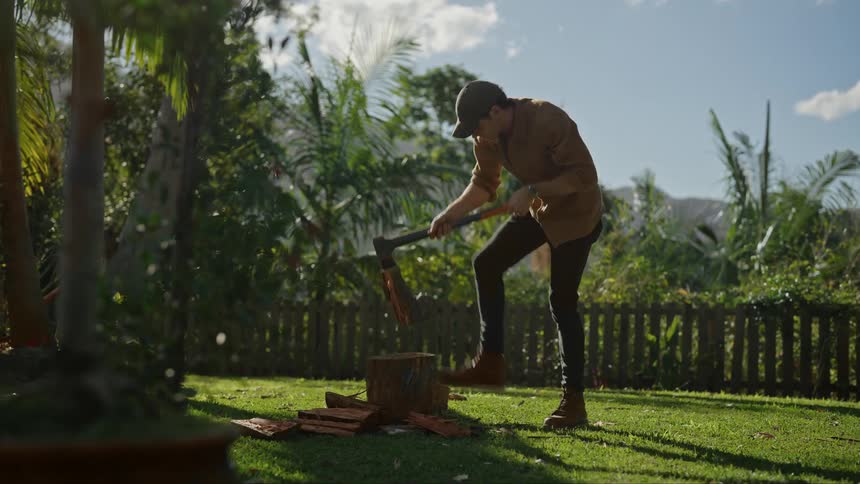 Young man chops wood over a stump with an axe