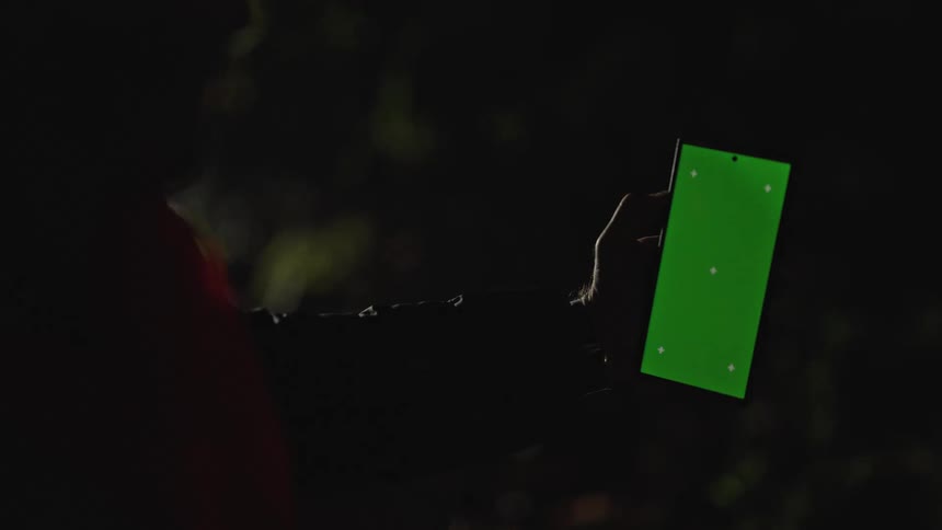 A man holding his cellphone and observing the perimeter during night work