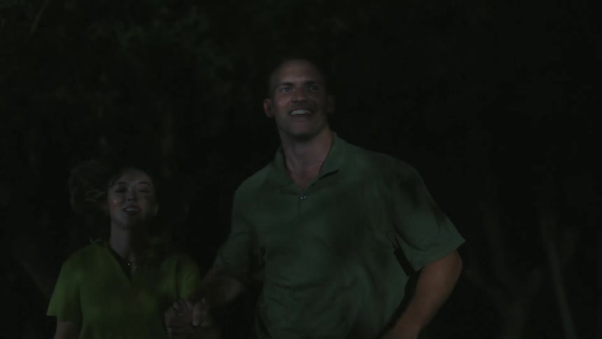 A man and a woman running smiling and holding hands at night