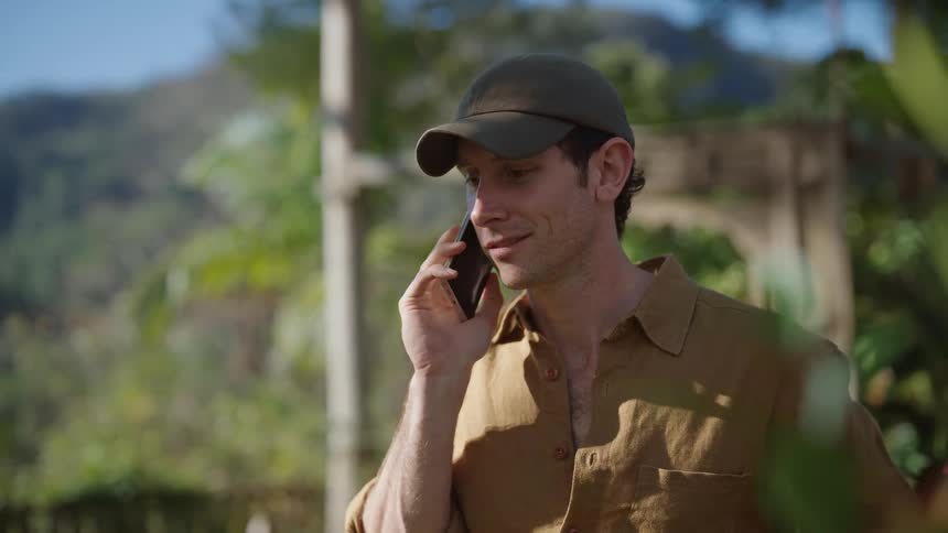 A man talks on his cell phone in a yard on a sunny day