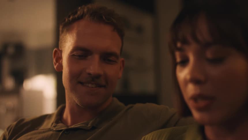 Happy man listens to his wife reading on the couch at home