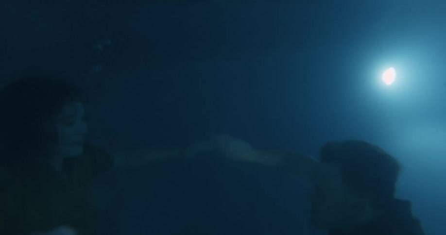 Two young people a woman and a man in the pool diving down and resurfacing