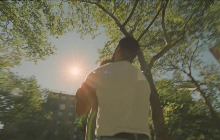 A father picking up the child and tossing them up playfully in an outdoor environment with trees and urban buildings