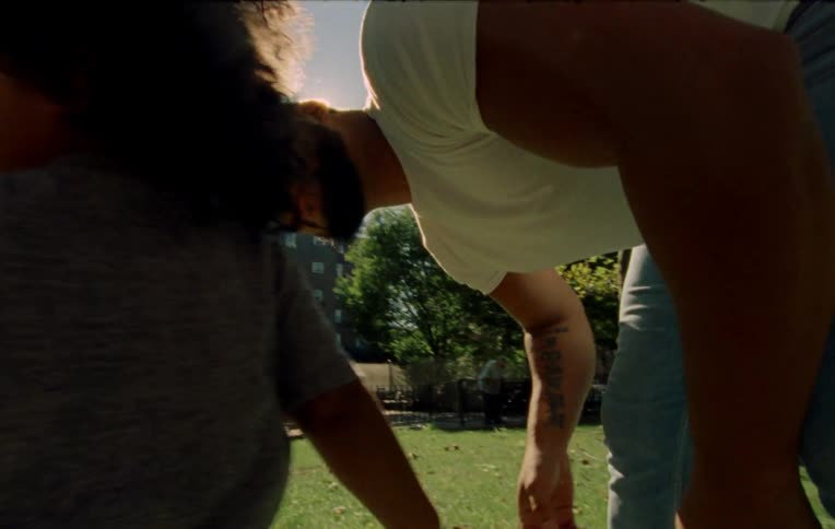 A father plays with his two small children in a park on a sunny day