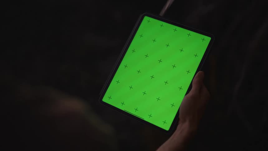 A tablet with a green screen with plus symbols being tapped by a finger