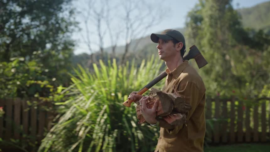 Man carrying an axe and chopped wood in the backyard