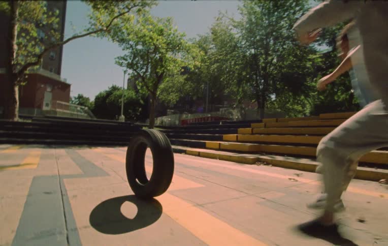 Three children descending a short staircase and throwing a moving vehicle tire running after it and playing joyfully