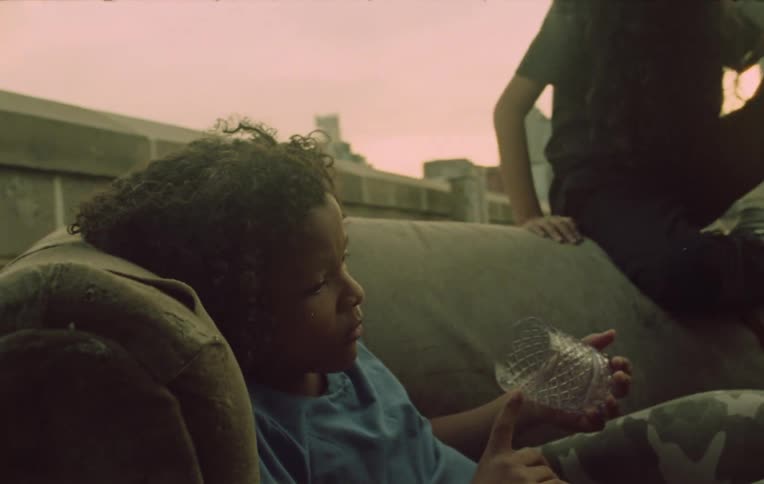 Two children on the sofa with one of them holding a glass and the other observing