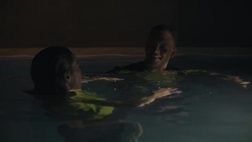 A man and a woman inside the pool talking to each other and smiling