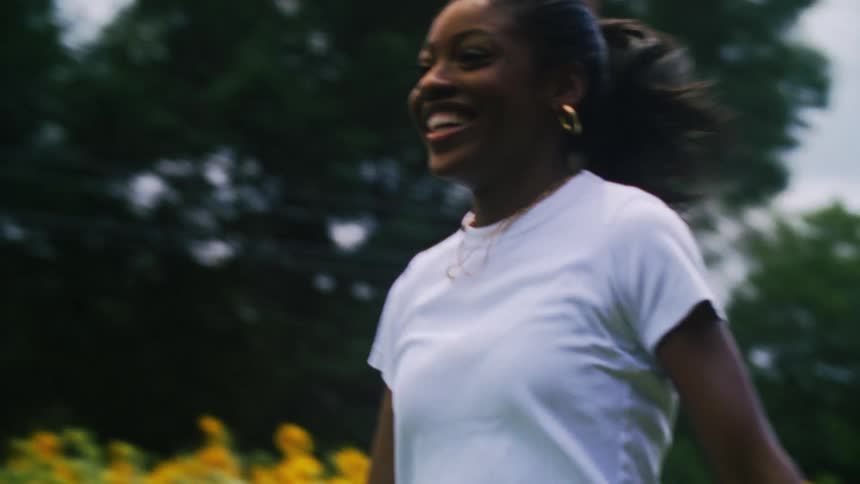 A young woman running across a field of sunflowers