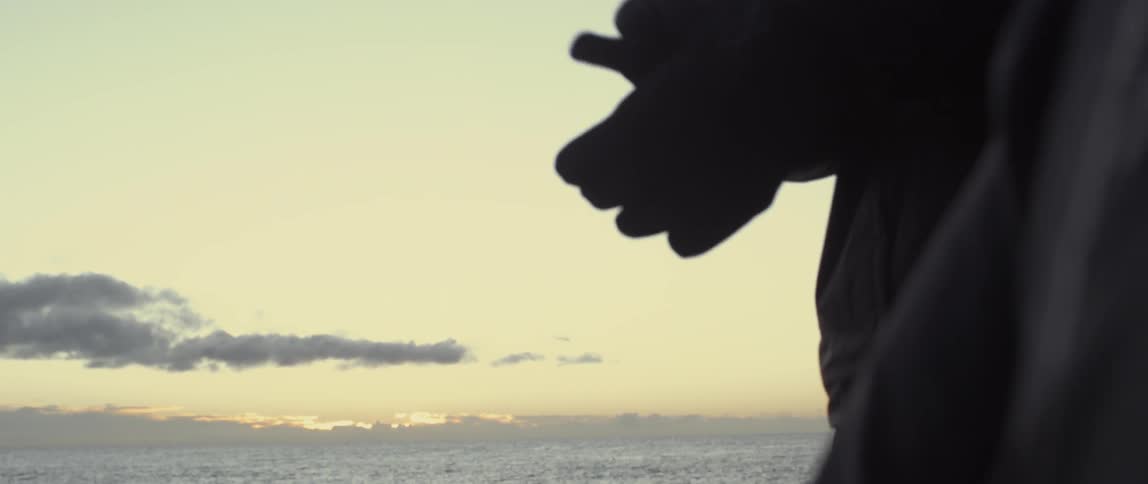 A person puts on gloves near the beach