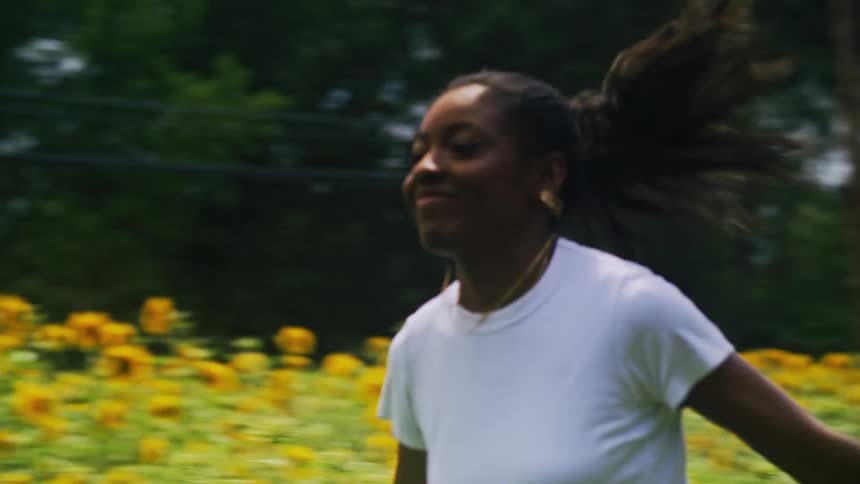 Woman running in a garden full of sunflowers