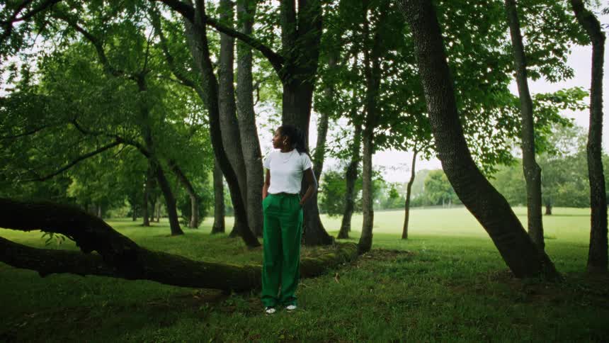 Woman surrounded by trees stands in a park