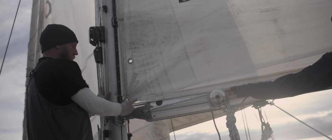 A man is fastening the sail on a boat