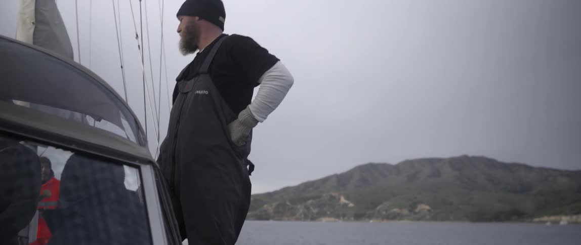 A man in coveralls riding in a boat
