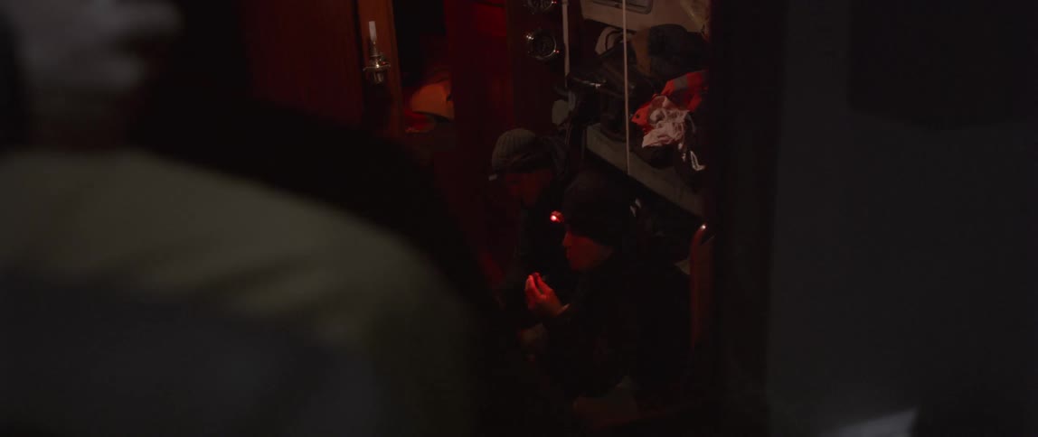 A person is crouched down below with a small light in the dark